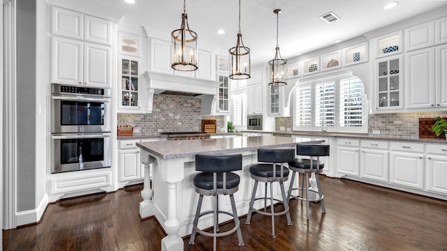 kitchen with appliances with stainless steel finishes, white cabinets, visible vents, and dark wood-type flooring