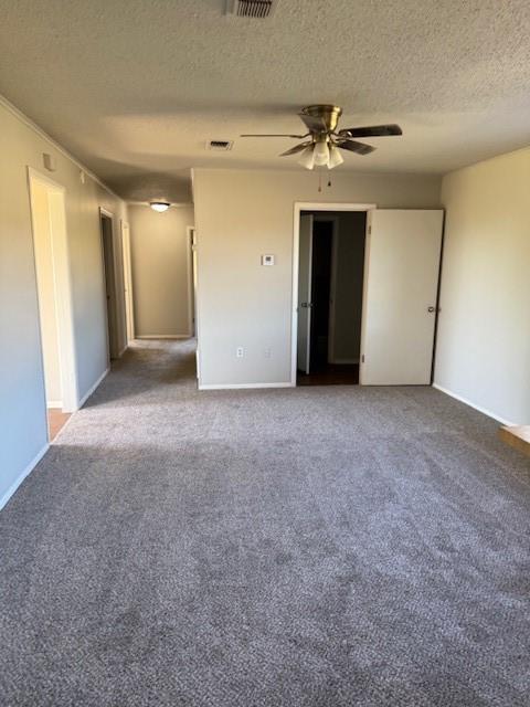 empty room with a ceiling fan, dark carpet, a textured ceiling, and baseboards