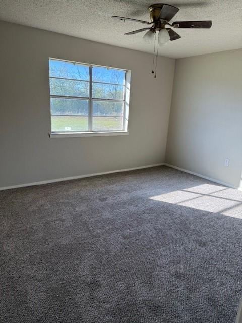 carpeted spare room with ceiling fan, a textured ceiling, and baseboards