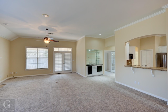 unfurnished living room featuring ornamental molding, light colored carpet, visible vents, and baseboards