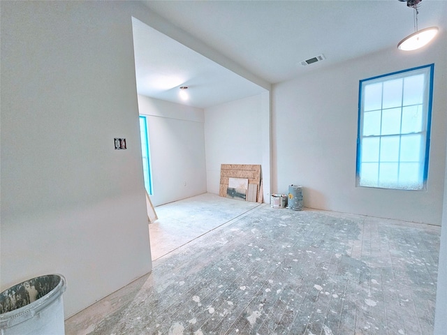 unfurnished room with visible vents, plenty of natural light, and a fireplace