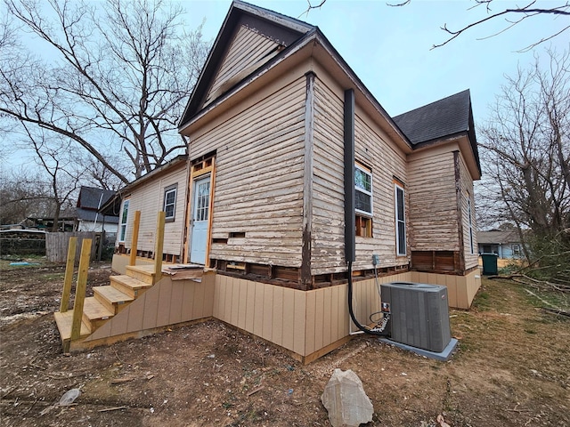 view of side of property with roof with shingles, cooling unit, and fence