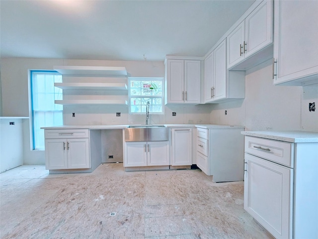 kitchen with light countertops, a sink, and white cabinetry