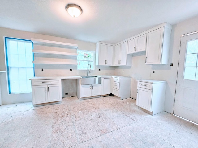 kitchen with light countertops, open shelves, a sink, and white cabinetry