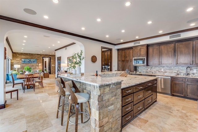 kitchen featuring a sink, visible vents, a large island, built in microwave, and dishwasher