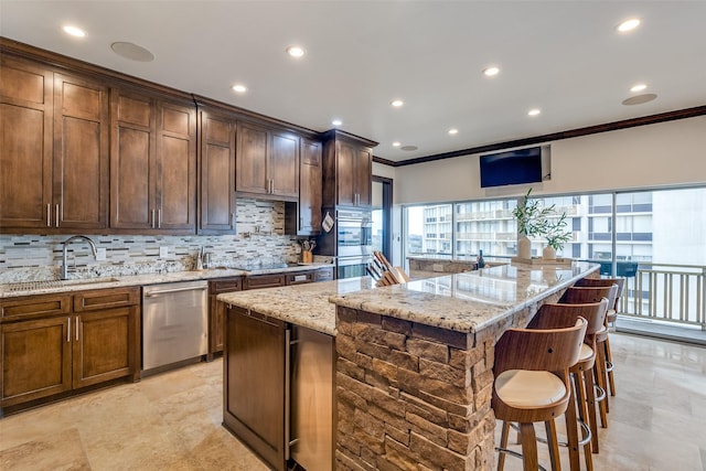 kitchen with light stone counters, a center island, decorative backsplash, appliances with stainless steel finishes, and a sink