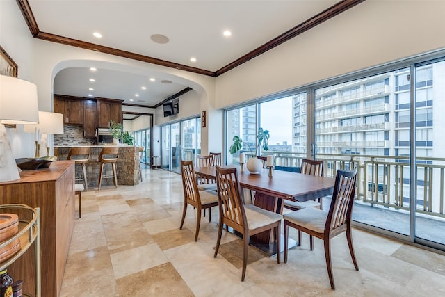 dining space with arched walkways, crown molding, and recessed lighting