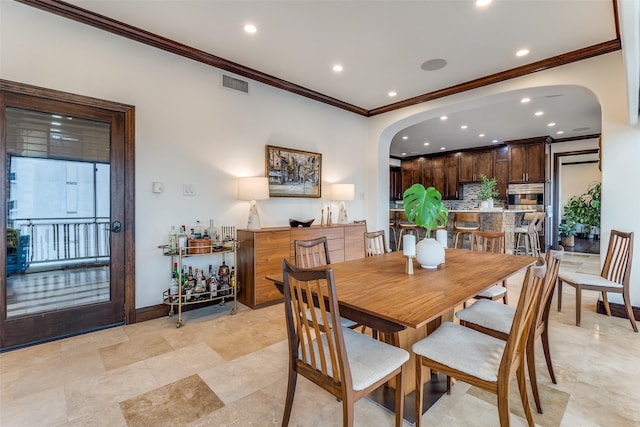 dining room featuring baseboards, visible vents, arched walkways, and crown molding