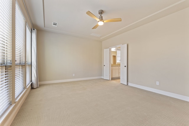 spare room featuring light colored carpet, ceiling fan, visible vents, and baseboards