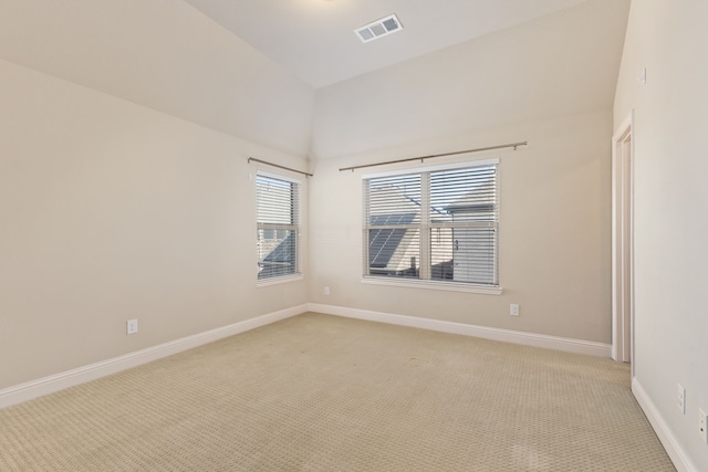 spare room with light carpet, vaulted ceiling, visible vents, and baseboards