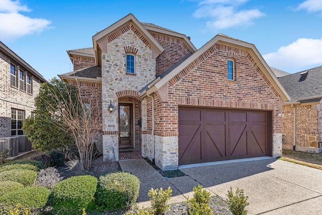 french provincial home featuring driveway, a shingled roof, stone siding, an attached garage, and brick siding