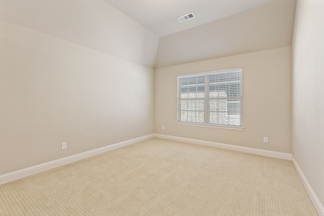 empty room featuring lofted ceiling, light carpet, visible vents, and baseboards