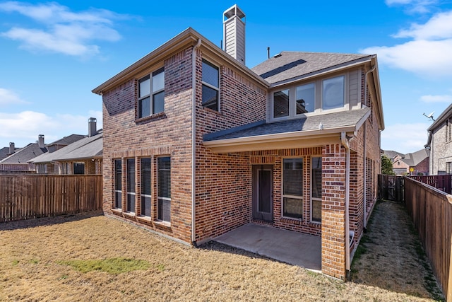 back of property featuring a shingled roof, a patio, a fenced backyard, a chimney, and brick siding