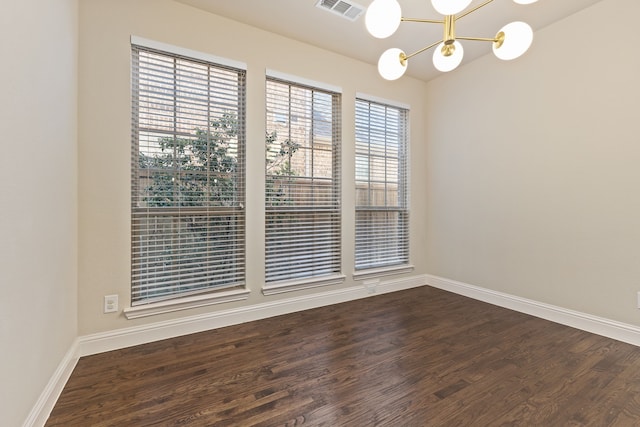 unfurnished room with visible vents, a notable chandelier, baseboards, and wood finished floors