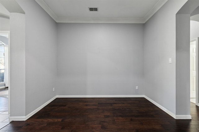 spare room featuring crown molding, dark wood finished floors, visible vents, and baseboards