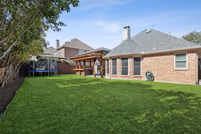 back of house with a fenced backyard, brick siding, a gazebo, a lawn, and a trampoline