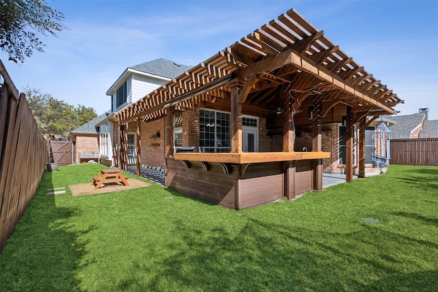 rear view of house featuring a yard, brick siding, a shingled roof, and a fenced backyard