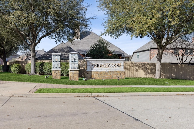 community / neighborhood sign with fence and a lawn