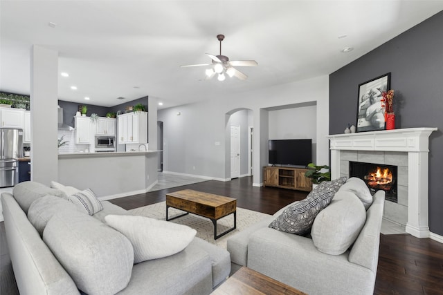 living room with arched walkways, recessed lighting, a fireplace, wood finished floors, and baseboards