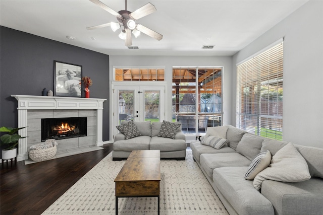 living area with a tile fireplace, french doors, visible vents, and wood finished floors