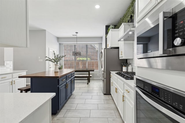 kitchen with butcher block countertops, backsplash, appliances with stainless steel finishes, white cabinetry, and blue cabinets