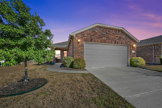 view of front facade with an attached garage, a front yard, concrete driveway, and brick siding