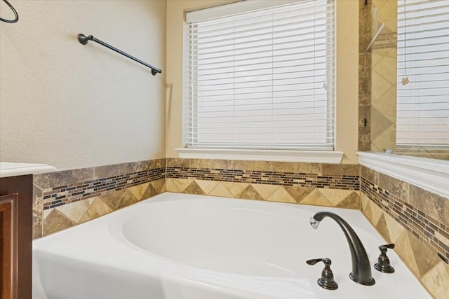 bathroom with a garden tub, a wealth of natural light, and vanity