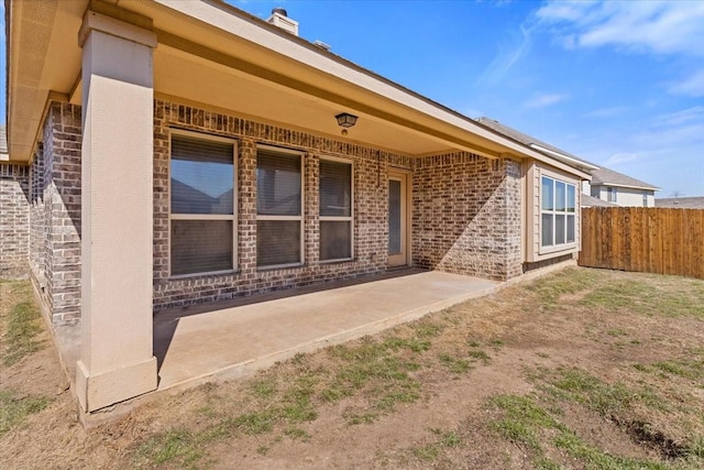 back of property with brick siding, a patio area, and fence