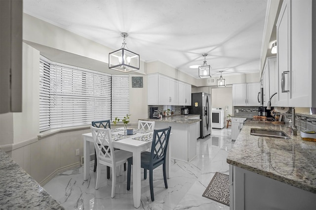 dining space with a wainscoted wall, washer / clothes dryer, marble finish floor, an inviting chandelier, and a textured ceiling