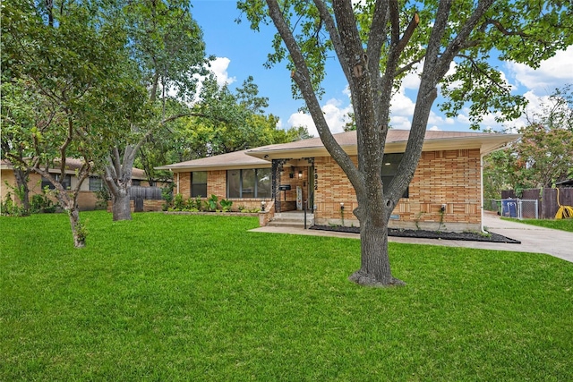 ranch-style house featuring brick siding, fence, and a front yard