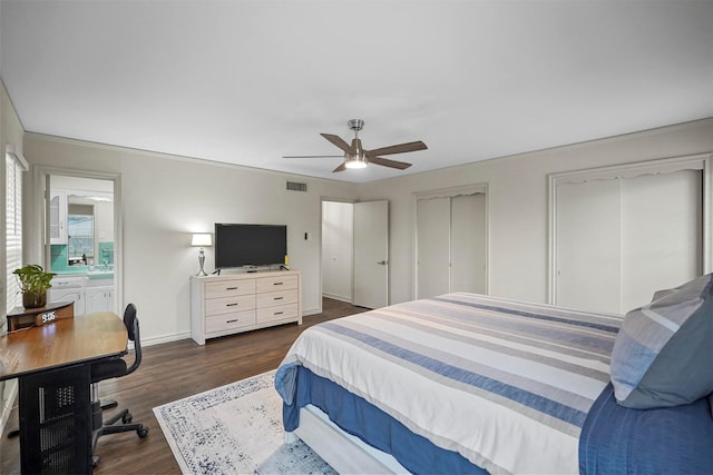 bedroom featuring baseboards, visible vents, dark wood finished floors, ceiling fan, and multiple closets