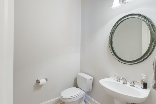 bathroom featuring toilet, baseboards, and a sink