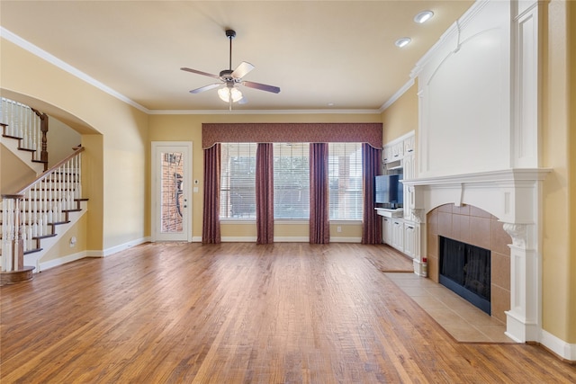 unfurnished living room featuring light wood-style floors, crown molding, a fireplace, and baseboards