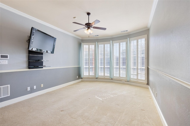 spare room with carpet floors, baseboards, visible vents, and crown molding