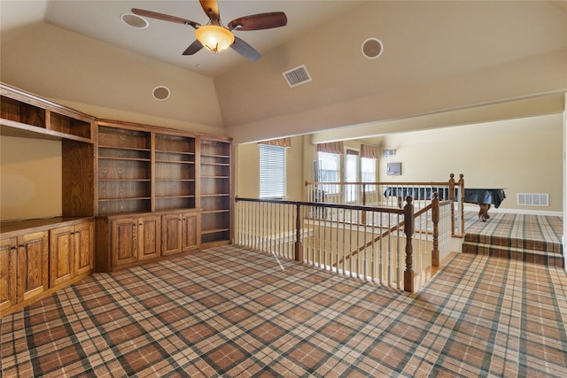 unfurnished room featuring lofted ceiling, visible vents, carpet flooring, and an upstairs landing