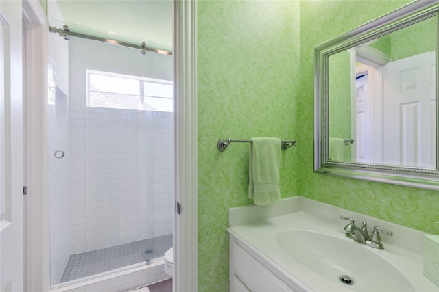 full bathroom featuring a stall shower, vanity, toilet, and wallpapered walls