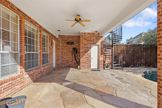 view of patio with ceiling fan, fence, and stairway