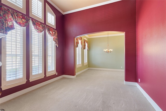 carpeted empty room with arched walkways, a notable chandelier, a high ceiling, baseboards, and crown molding