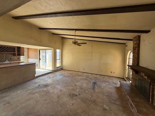 unfurnished living room with concrete flooring, a brick fireplace, beam ceiling, and a ceiling fan