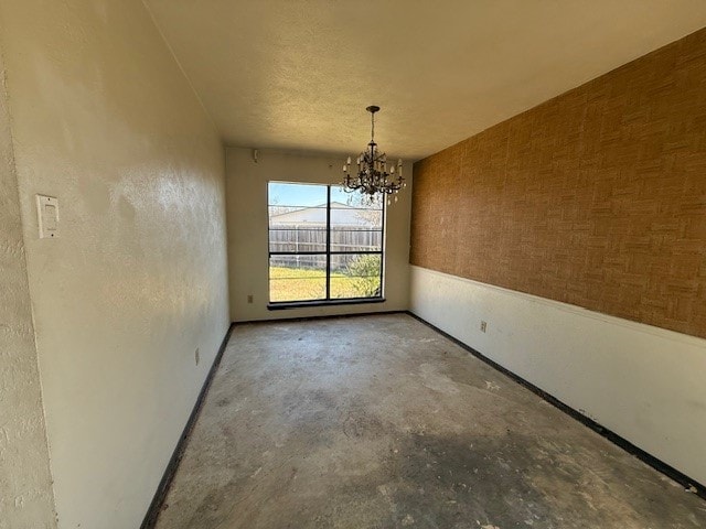 unfurnished dining area featuring a chandelier and unfinished concrete flooring