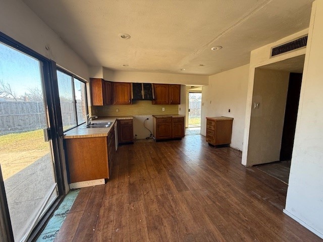 kitchen featuring tasteful backsplash, visible vents, brown cabinetry, dark wood-type flooring, and light countertops