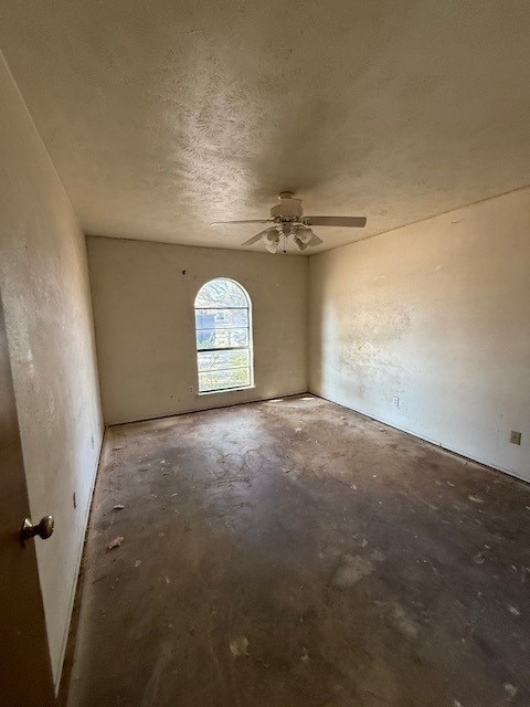 unfurnished room featuring concrete flooring, a textured ceiling, and a ceiling fan