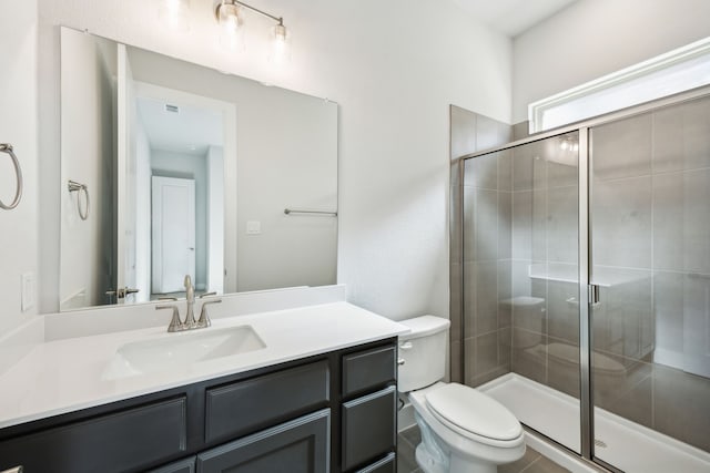 bathroom featuring vanity, a shower stall, and toilet