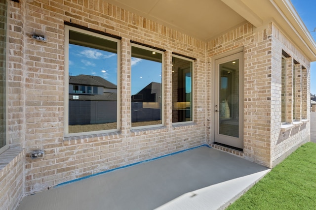 view of exterior entry featuring a patio area and brick siding