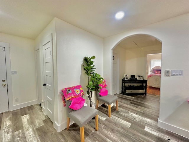 corridor with arched walkways, wood finished floors, and baseboards