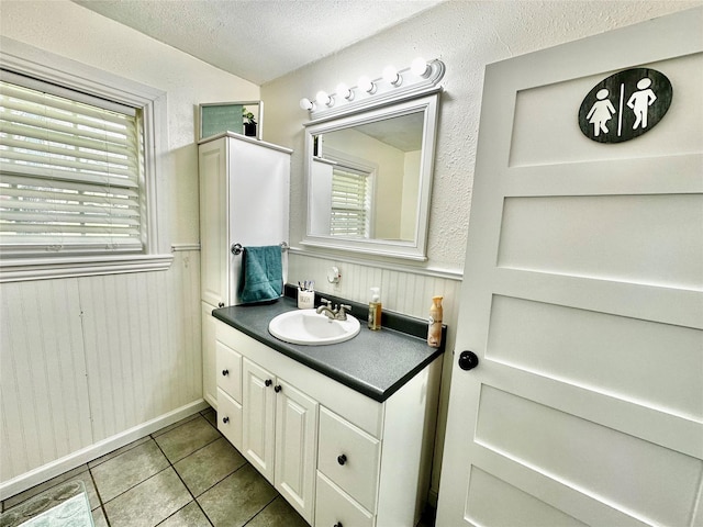 bathroom with a textured ceiling, a wainscoted wall, vanity, and tile patterned floors