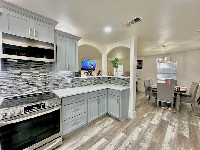 kitchen featuring stainless steel appliances, visible vents, light wood finished floors, and gray cabinetry