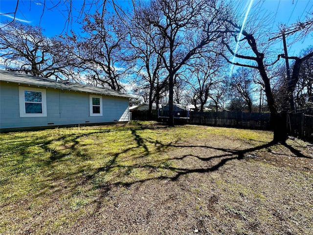 view of yard featuring a trampoline and fence