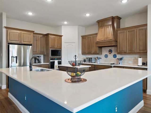 kitchen featuring dark wood finished floors, a large island, stainless steel appliances, a sink, and premium range hood