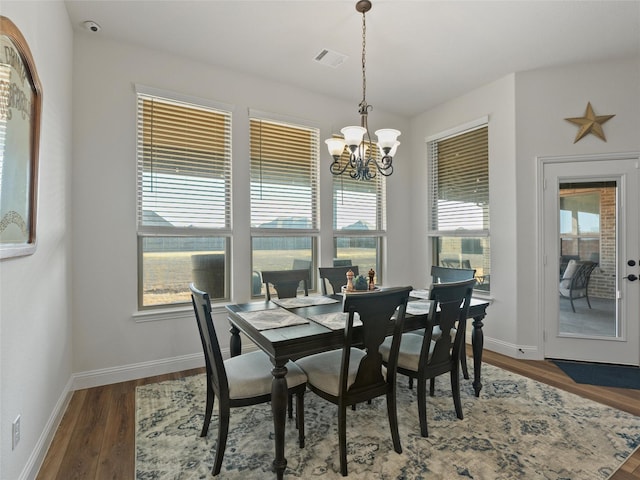 dining space with an inviting chandelier, visible vents, baseboards, and wood finished floors